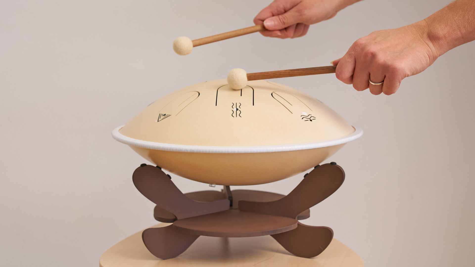 Hands playing a Moon Tone steel tongue drum resting on a lap